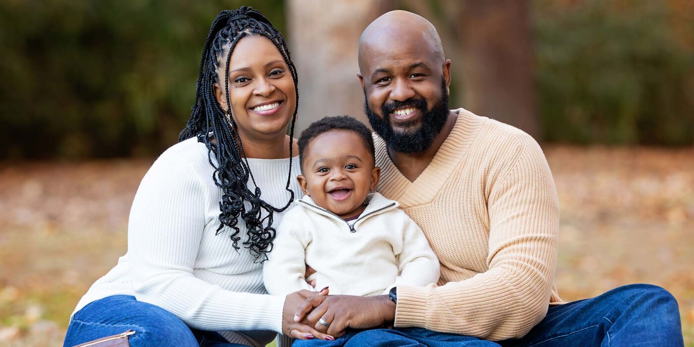Arlene Brown poses outside with her husband and baby