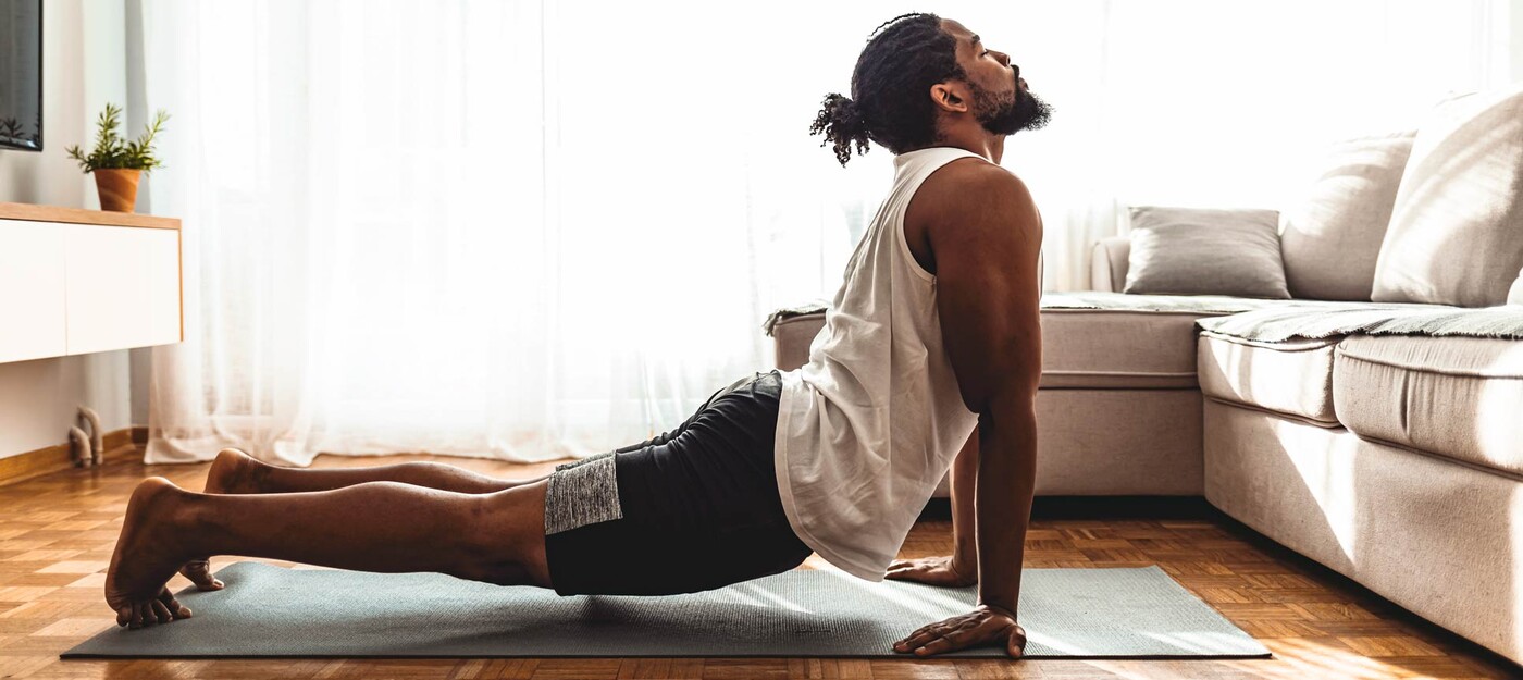 A man holds a upward facing dog yoga pose to stretch his back