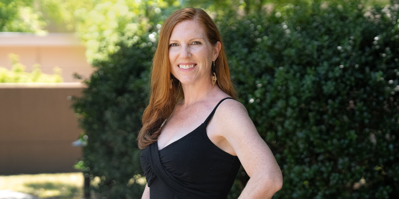 Jess Ruff smiles outside in front of some greenery