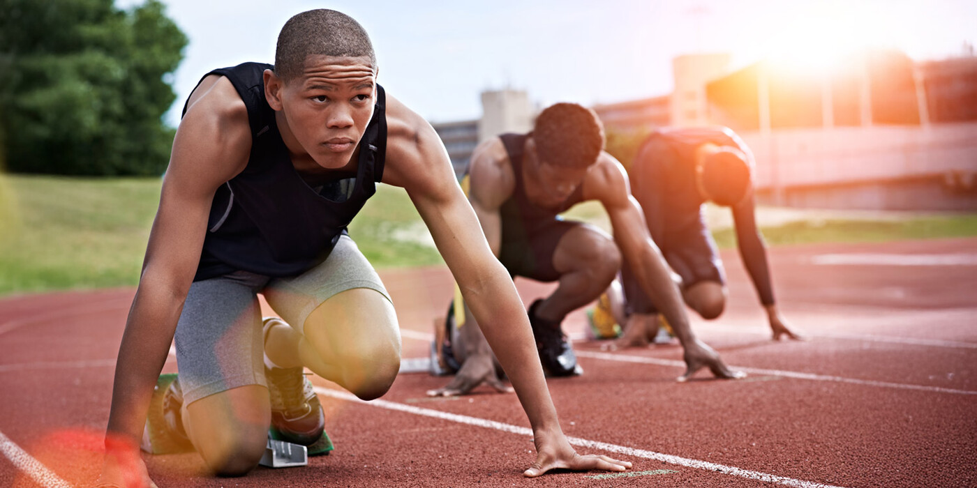 Male athletes line up in starting blocks on a track