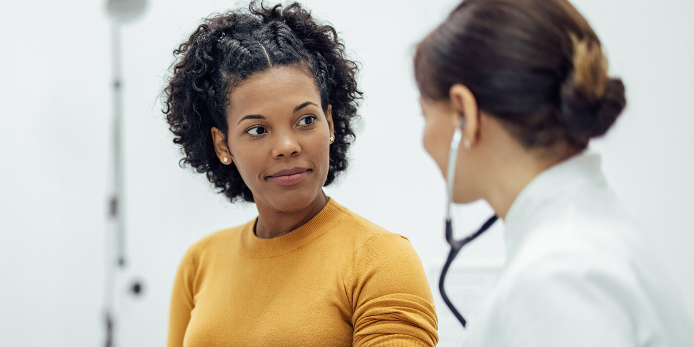 A woman listens to a doctor in a clinic room