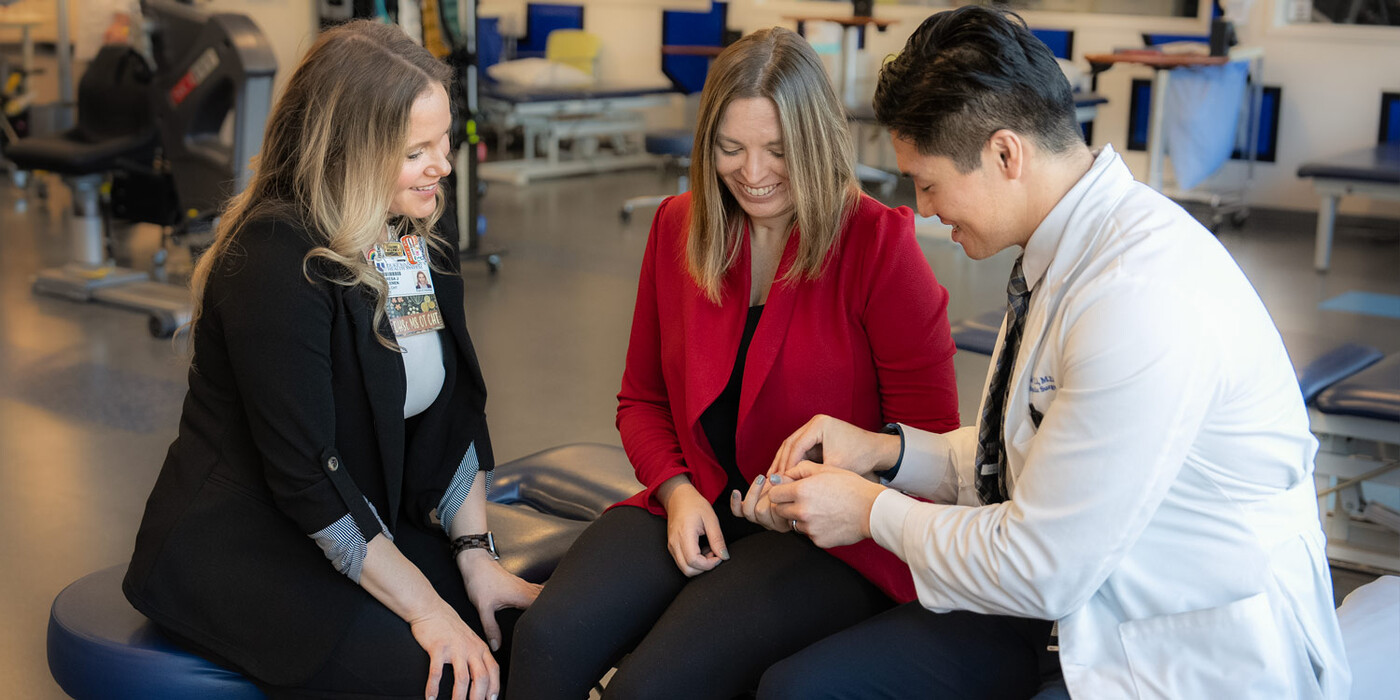 Occupational therapist Theresa Hallenen and orthopaedic and peripheral nerve surgeon Neill Li examine Jessi Wood's hand during an occupational therapy session..