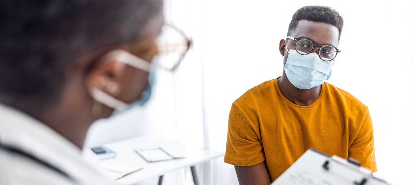 A doctor reviews a chart with a young adult male patient 