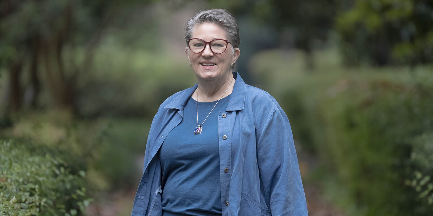 Anna Smith smiles in front of greenery