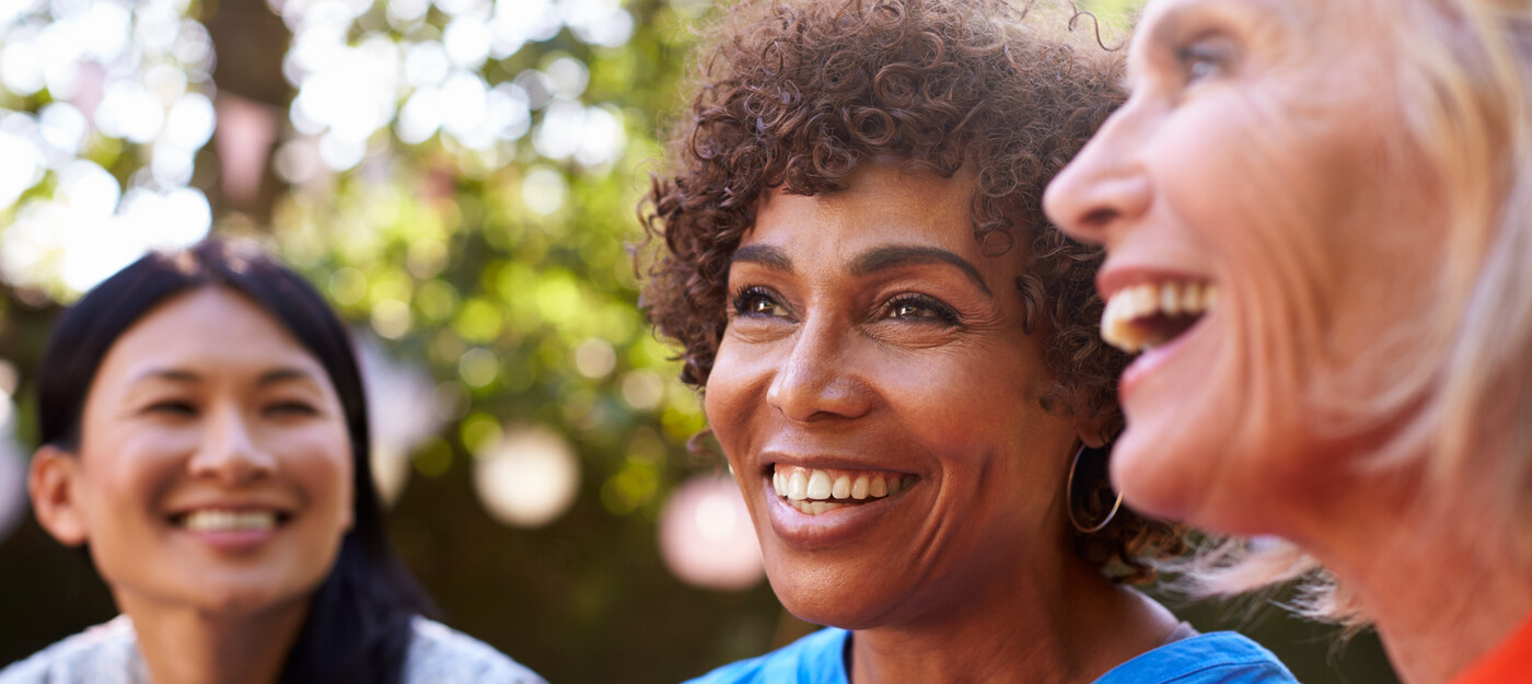 Three women smile together outside