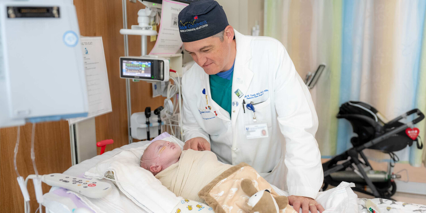 A doctor smiles at a baby in a hospital bed