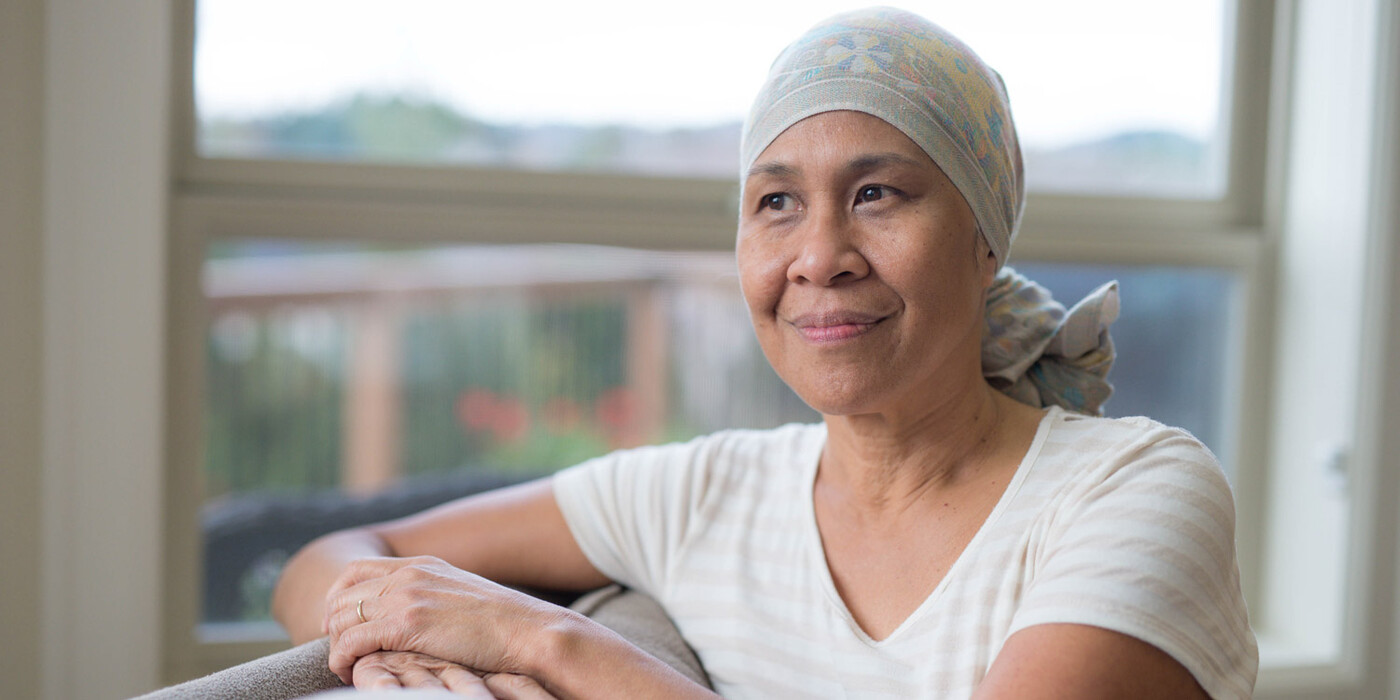 A woman wearing a head scarf looks out a hospital window