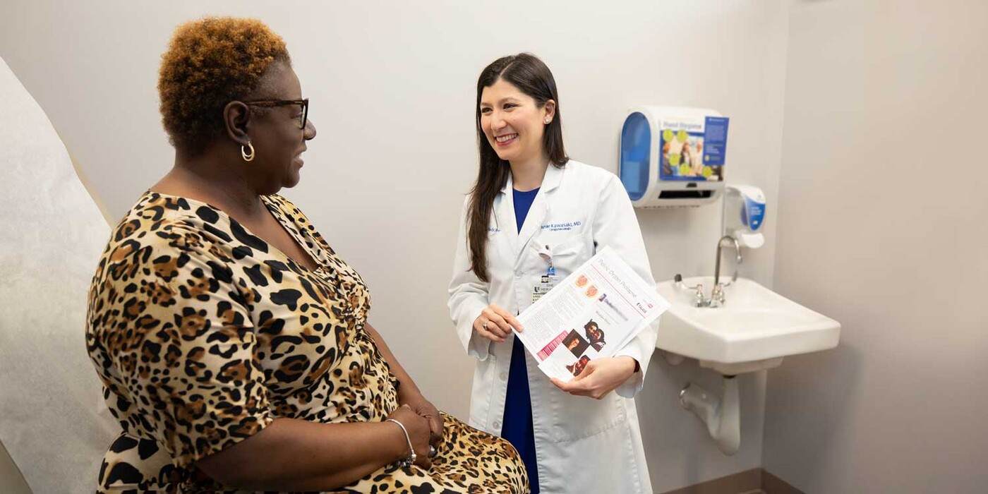 A doctor goes over some papers on pelvic floor disorders with a patient in a clinic room