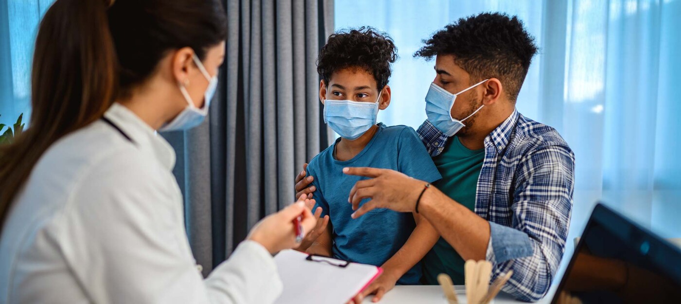 A female provider speaks with a young male patient and his father