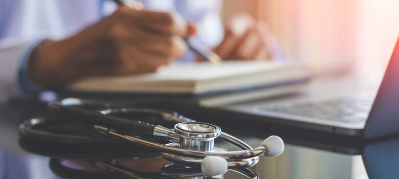 A provider takes notes while working on a laptop