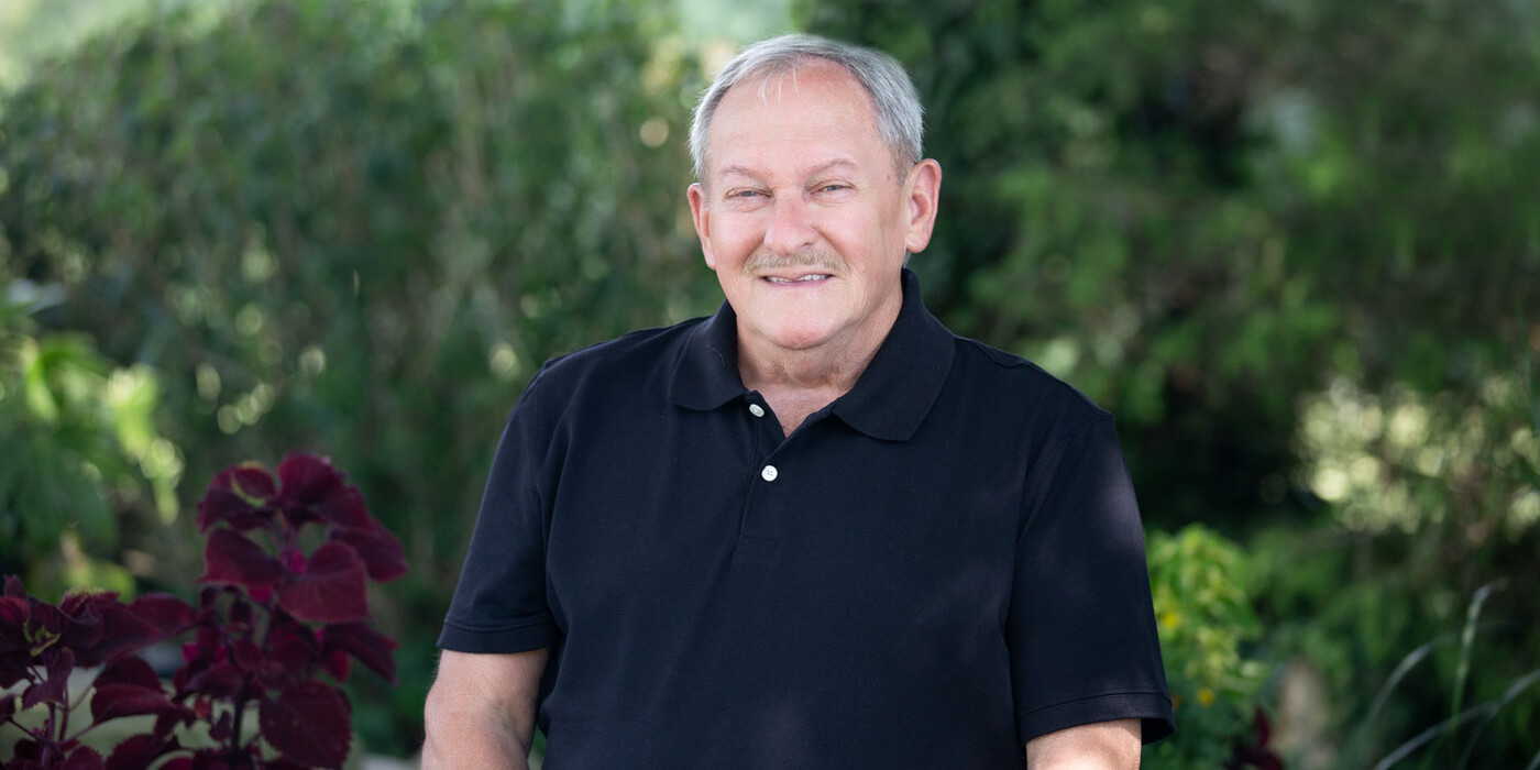 Dale Jessup smiles in front of some greenery.