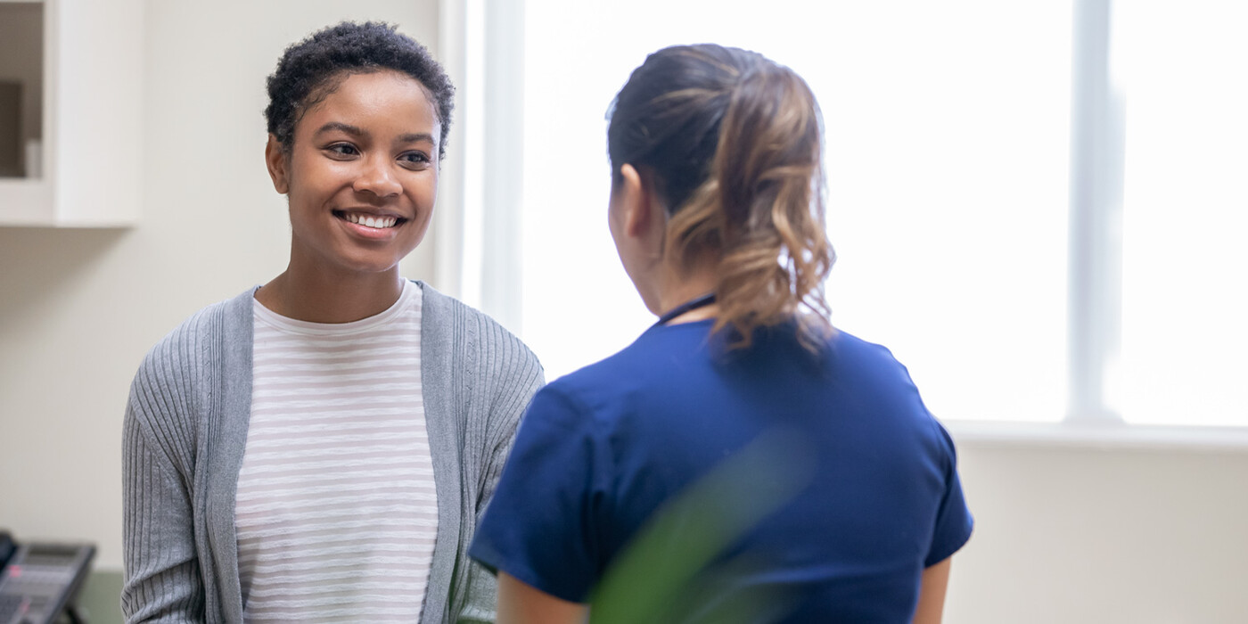 A female patient speaks to a female nurse at a clinic