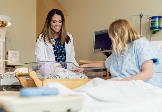 A physician looks at a newborn with the child's mother