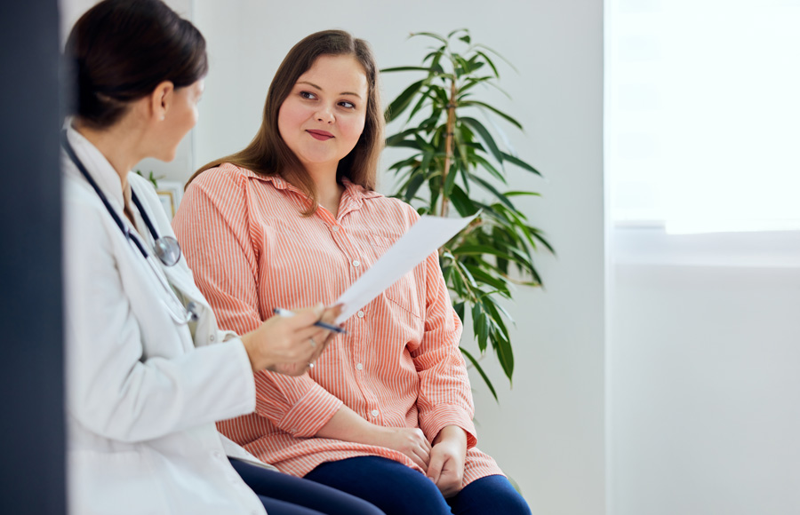 A doctor speaks with a woman in a clinic room