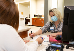 An administrator helps a patient check in 